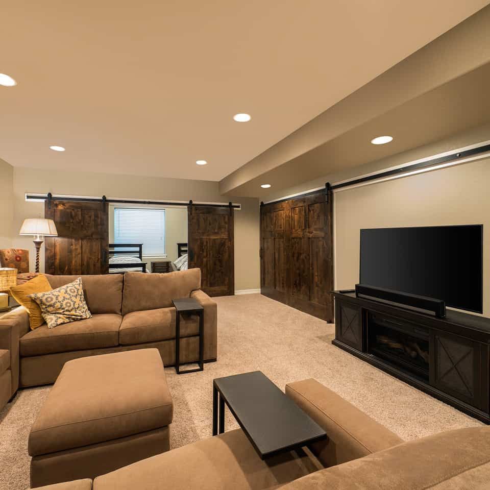 Living room with tan sectional, fireplace, TV, and rustic sliding doors.