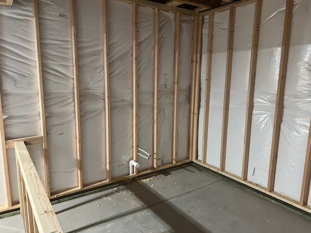 Framed walls with insulation in a basement. A PVC pipe is visible.