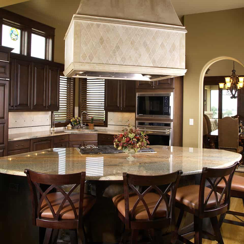 Kitchen with large island, dark wood cabinets, granite countertops, and bar stools.