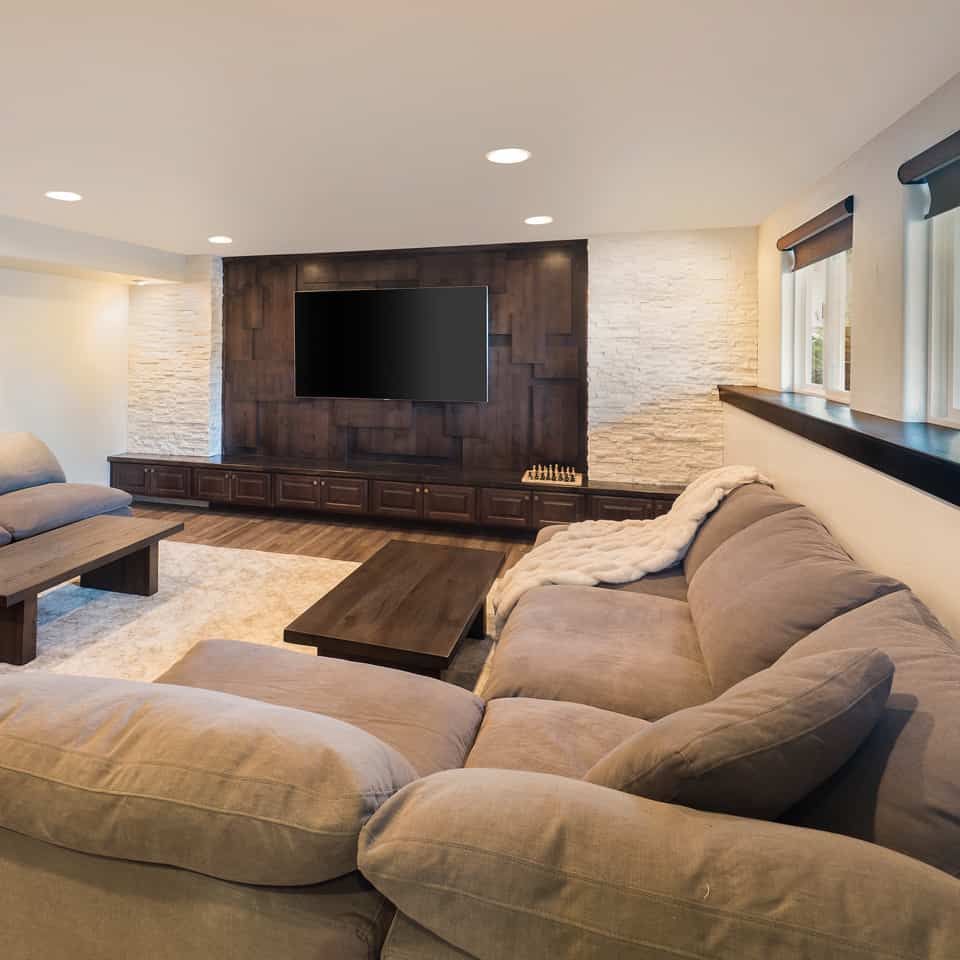 Cozy living room with sectional sofa, TV on wood panel wall, and rug on wood floor.