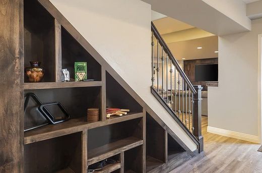 Built-in wooden shelving under stairs with items, adjacent to a staircase and hallway.