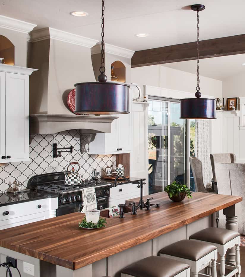 Kitchen with island, pendant lights, white cabinets, stainless steel appliances, and wooden countertops.