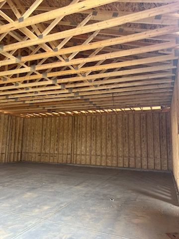 Empty wood-framed garage interior; walls, floor, and ceiling visible.