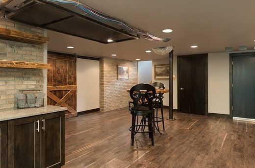 Basement with bar area, brick walls, and dark wood accents. Includes stools and a sliding barn door.