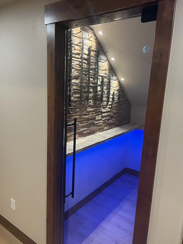 Glass door to wine cellar with brick wall and blue lighting.