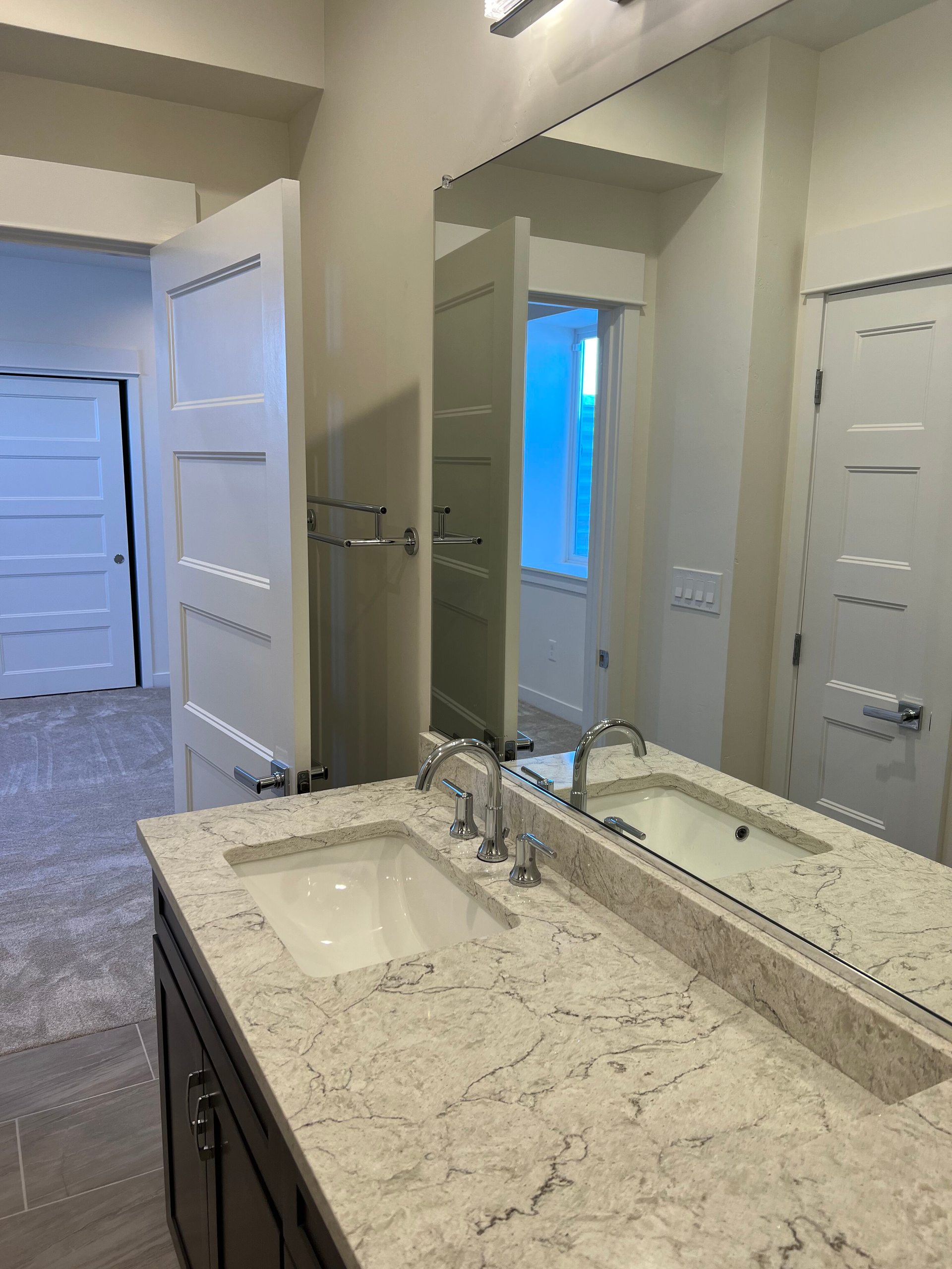 Bathroom with a marble countertop vanity, large mirror, and white doors.