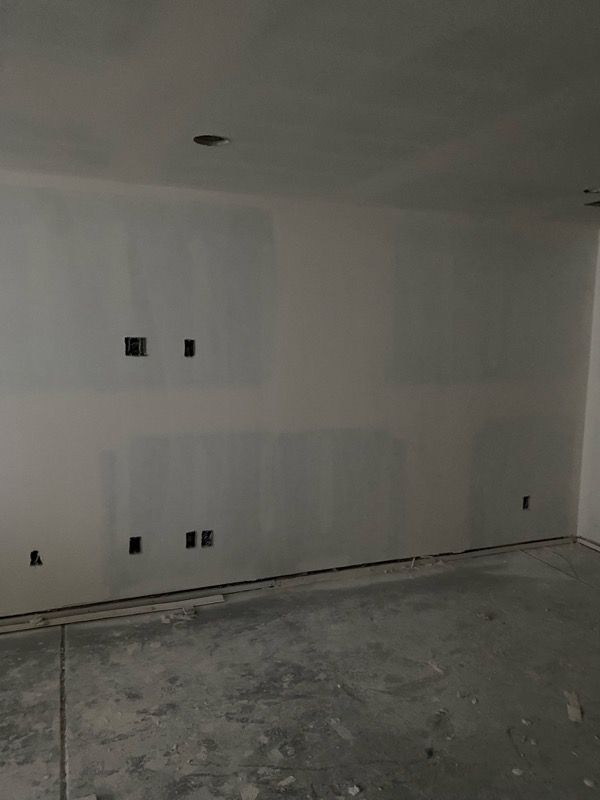 A room under construction with drywall, electrical outlets, and a concrete floor.
