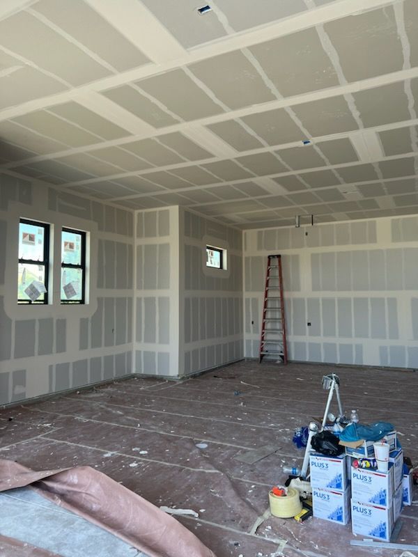 Interior of a room under construction; drywall installed on walls and ceiling, unfinished concrete floor.