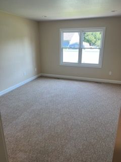 Empty room with beige carpet, neutral walls, and a window.