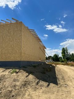 Construction of a building with wood paneling under a blue sky.