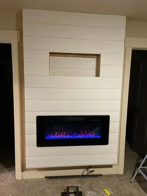 Electric fireplace built into a white plank wall with a blue flame display.