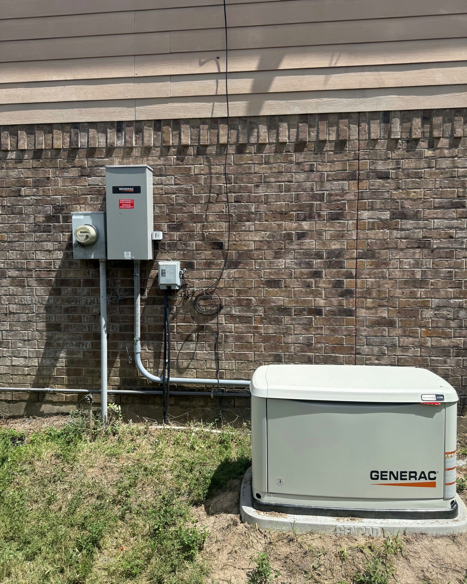 Generac home generator next to brick wall with electrical components.