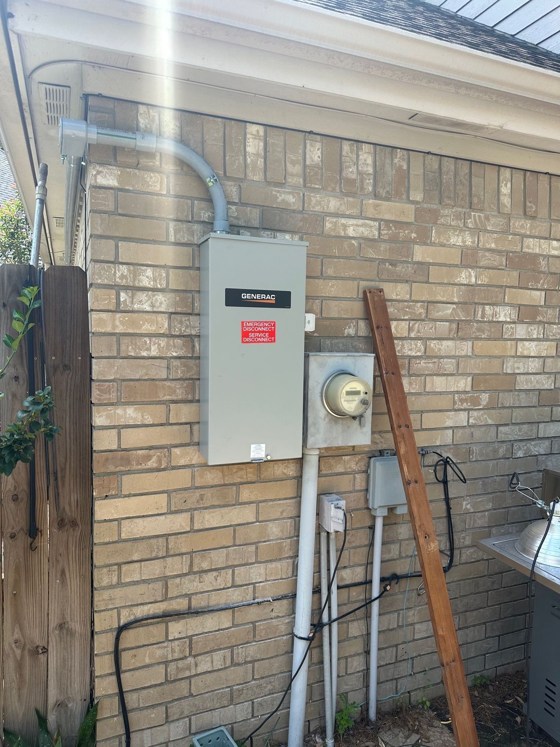 Electrical panel and meter box mounted on a brick wall. Gray boxes with conduit and wires.