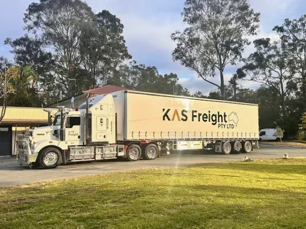 A large white truck with the word kas freight on the side is parked on the side of the road.