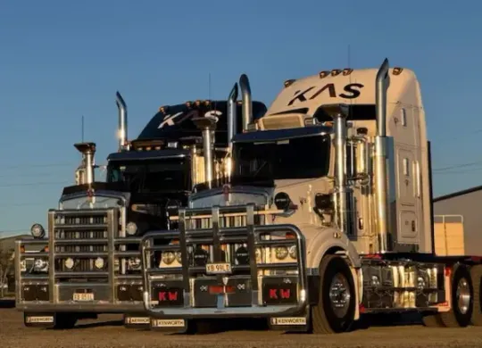 Two semi-trucks with the KAS Freight logo on them are parked next to each other