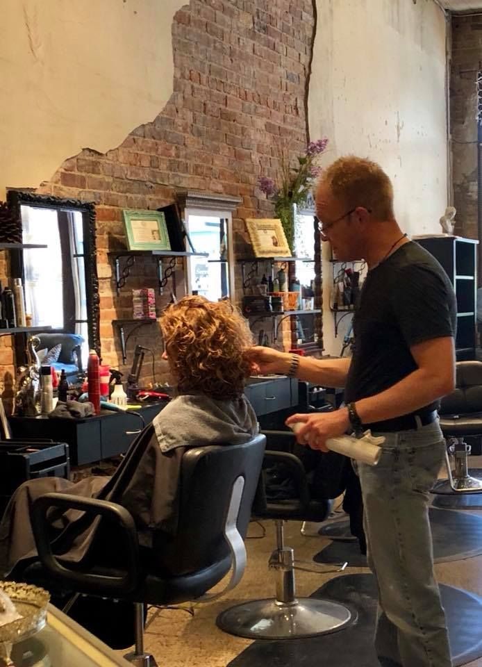 A man is cutting a woman 's hair in a salon