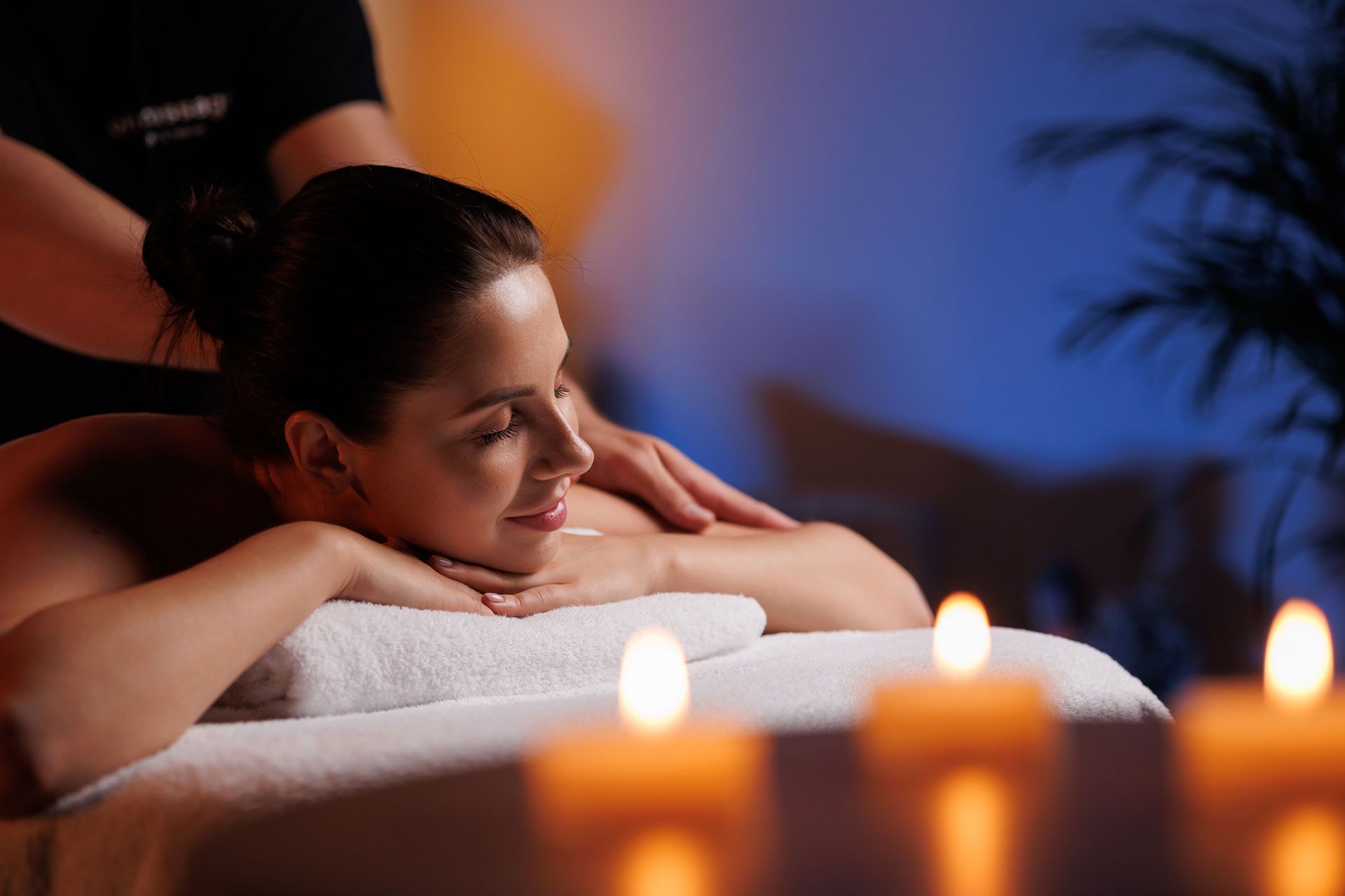 Woman receiving a relaxing spa massage with candles glowing in the foreground
