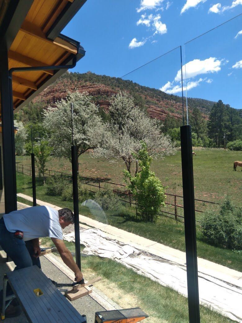 A man is working on a glass fence on a sunny day