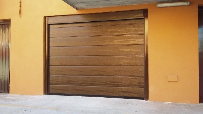 una porta del garage marrone è appoggiata a un muro arancione .