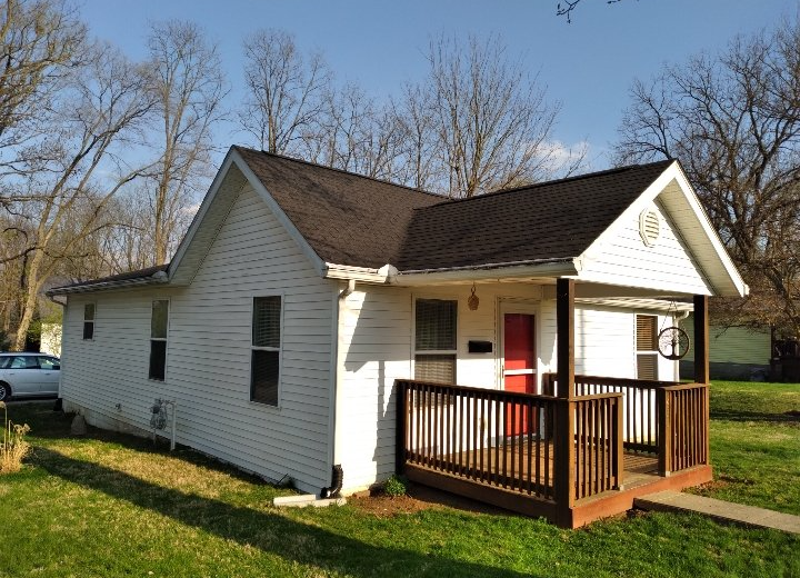 A small white house with a red door and a porch.