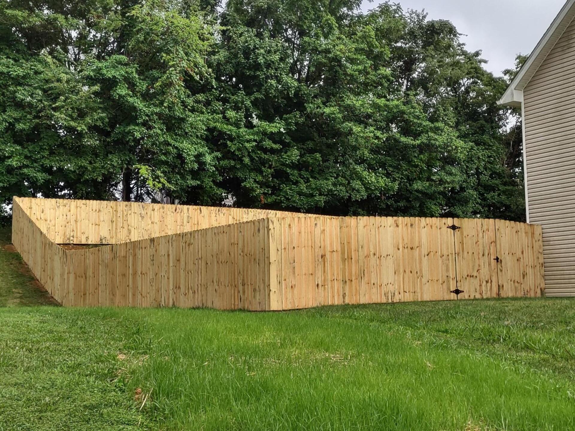 A wooden fence is sitting on top of a lush green lawn in front of a house.