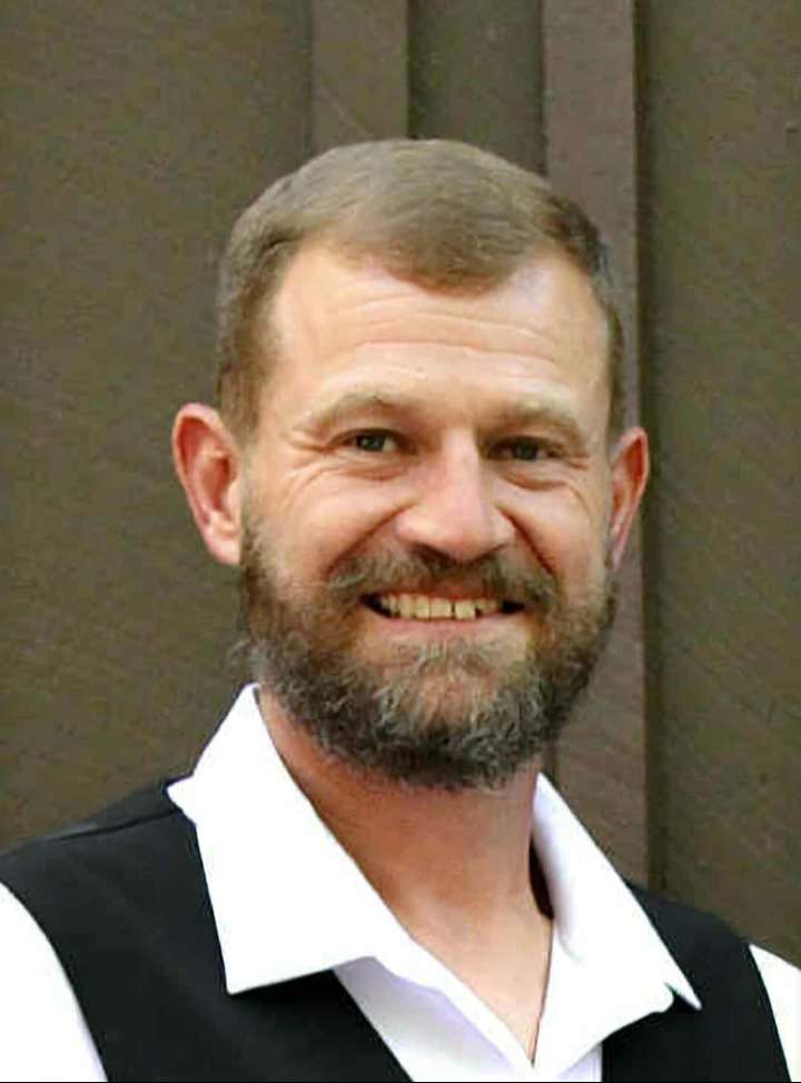 A man with a beard wearing a white shirt and red tie