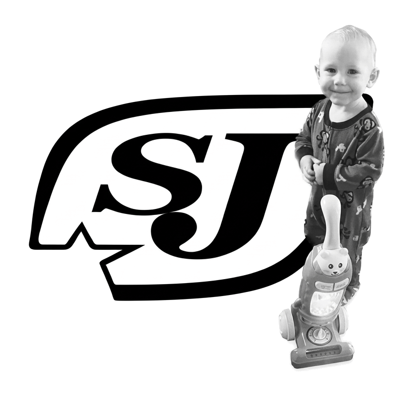 Child standing on a toy scooter beside a large SJ logo