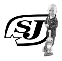 Child standing on a toy scooter beside a large SJ logo