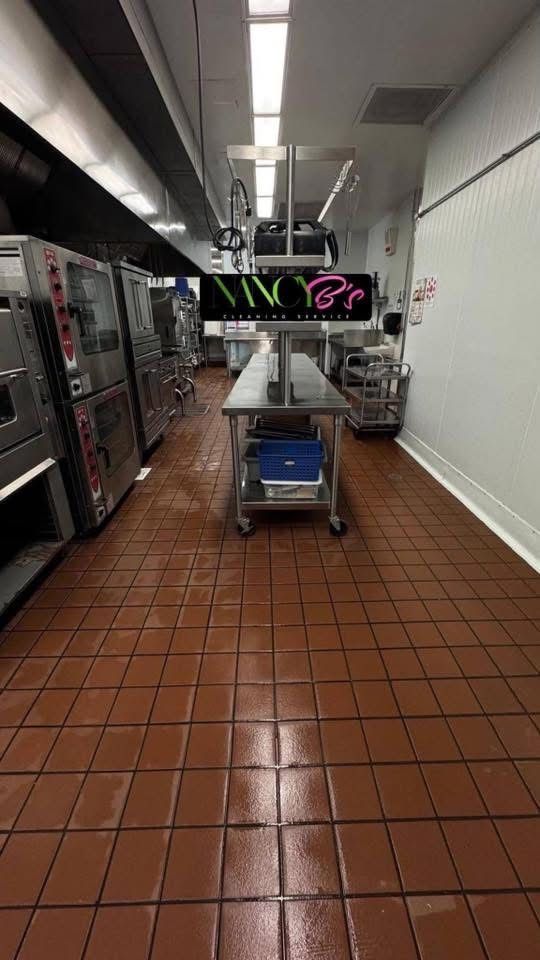 Commercial kitchen corridor with tiled floor, stainless equipment, and a cart under bright overhead lights