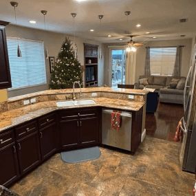 Open kitchen with dark cabinets, stone island, Christmas tree, and living room in the background