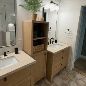 Modern bathroom with two sinks, mirrors, a wooden cabinet, and potted plant on top