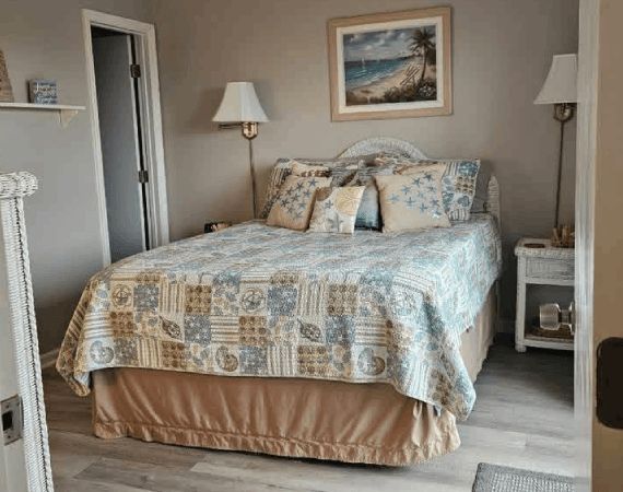 Cozy bedroom with a neatly made bed, soft blue patterned bedding, and matching lamps and framed art