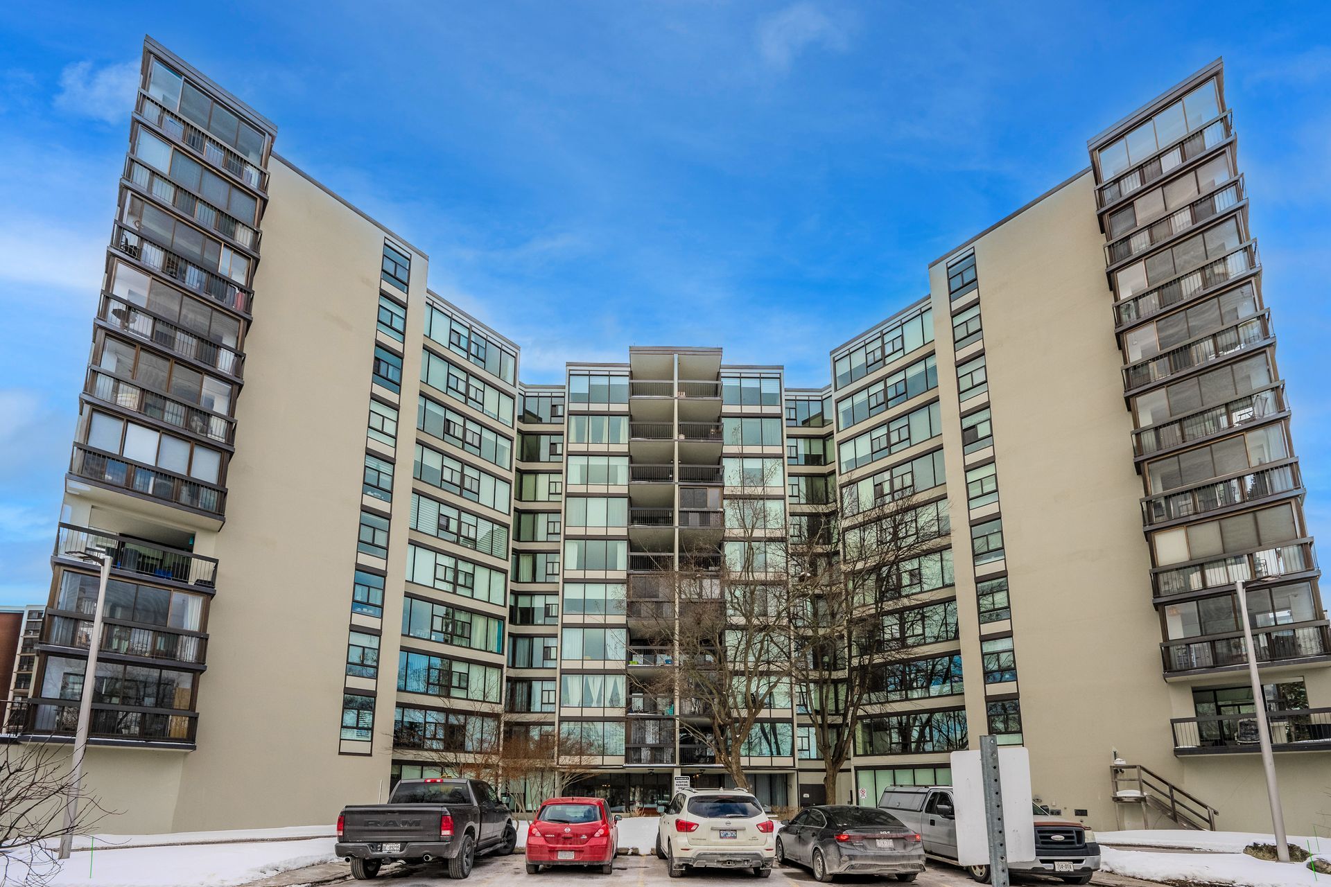 Modern apartment complex courtyard with parked cars under a blue winter sky