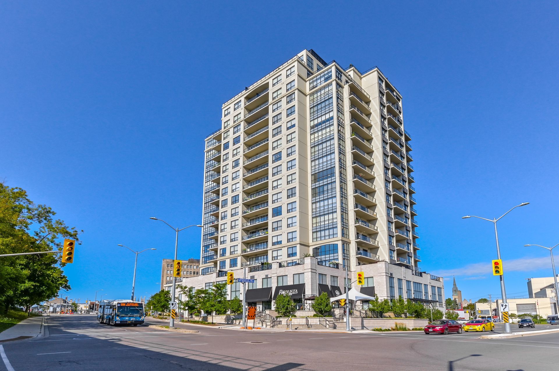 Tall white high-rise building on a sunny street corner under a clear blue sky