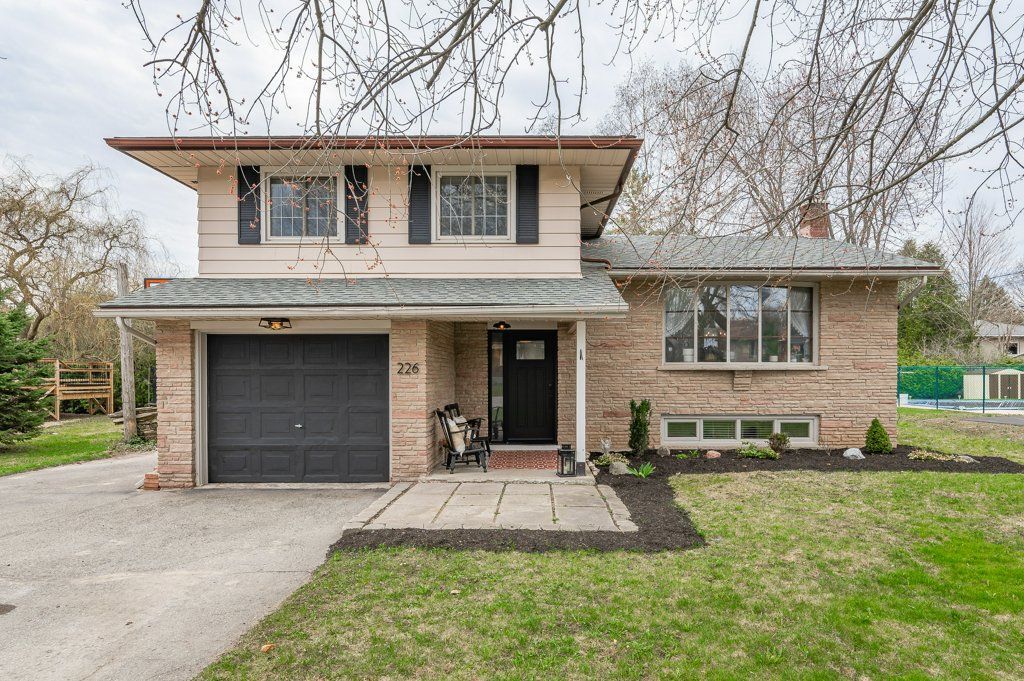 Two-story suburban house with brick and siding, black garage door, and a front lawn
