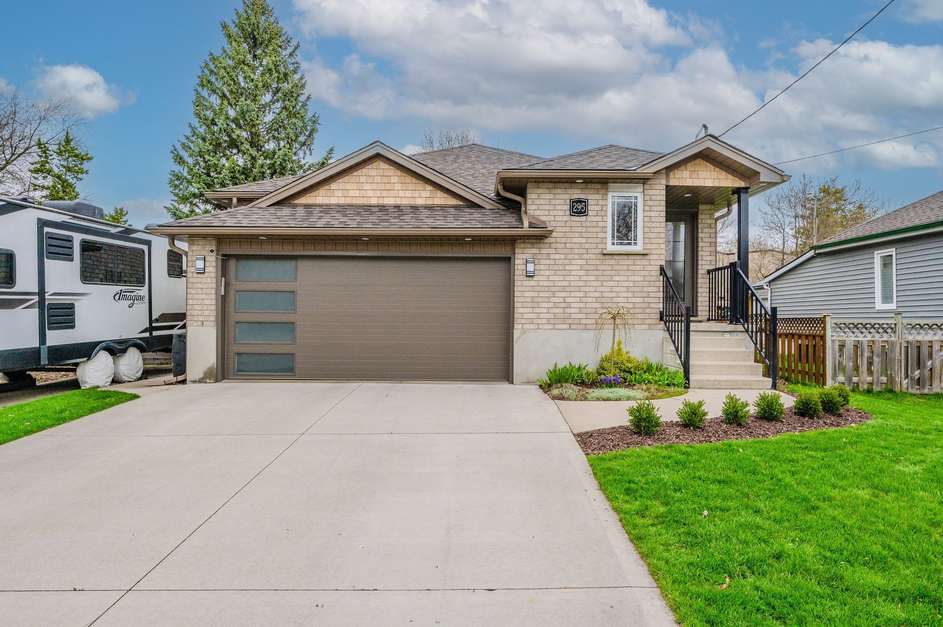 Suburban house with a two-car garage, concrete driveway, and green lawn under a partly cloudy sky