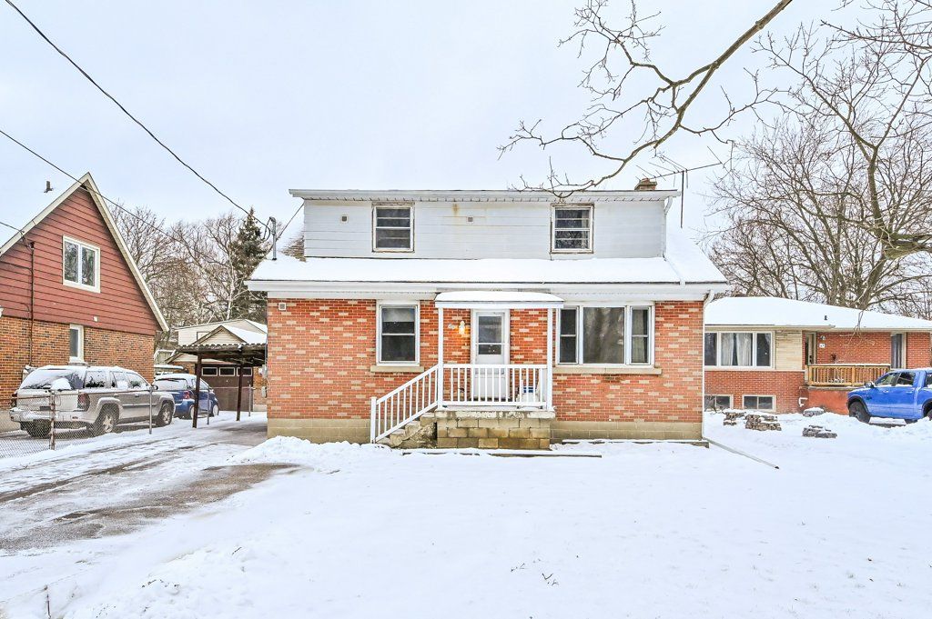 Snow-covered brick house with white trim and a small porch on a winter day