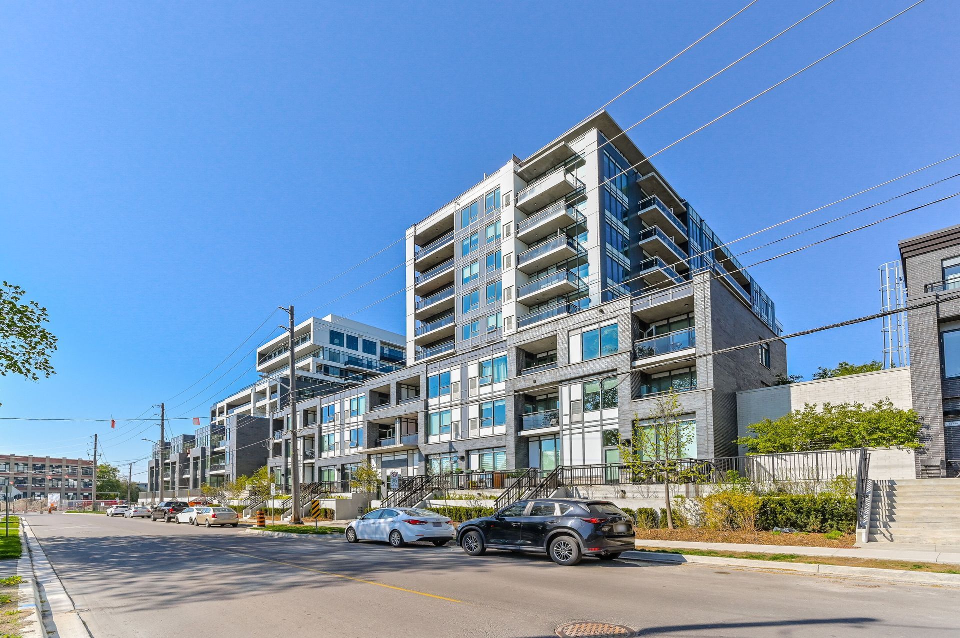Modern apartment buildings on a sunny street with parked cars and clear blue sky