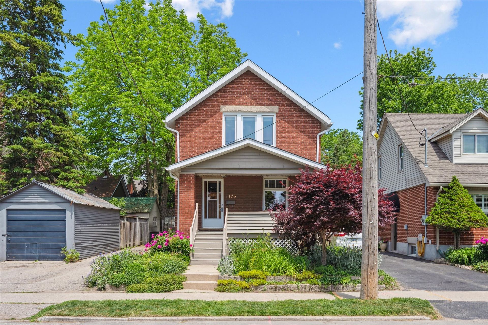 Red brick house with porch and garage on a sunny residential street