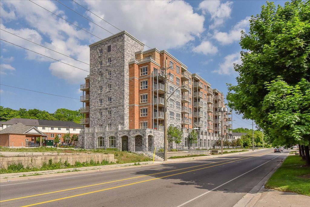 Modern apartment buildings beside a quiet road, with trees and a blue sky
