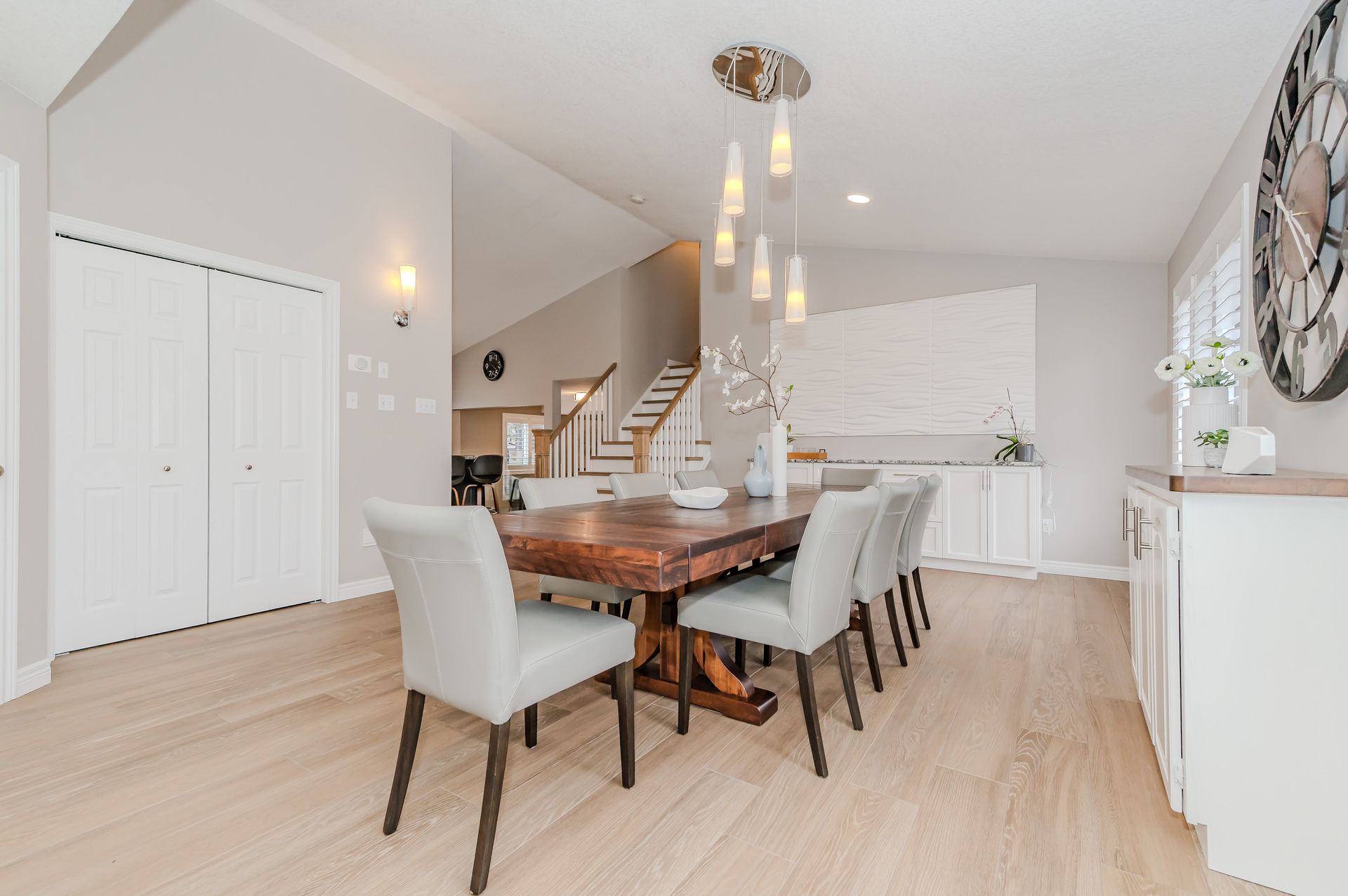 Bright dining room and open staircase in a modern home with light wood floors and white walls