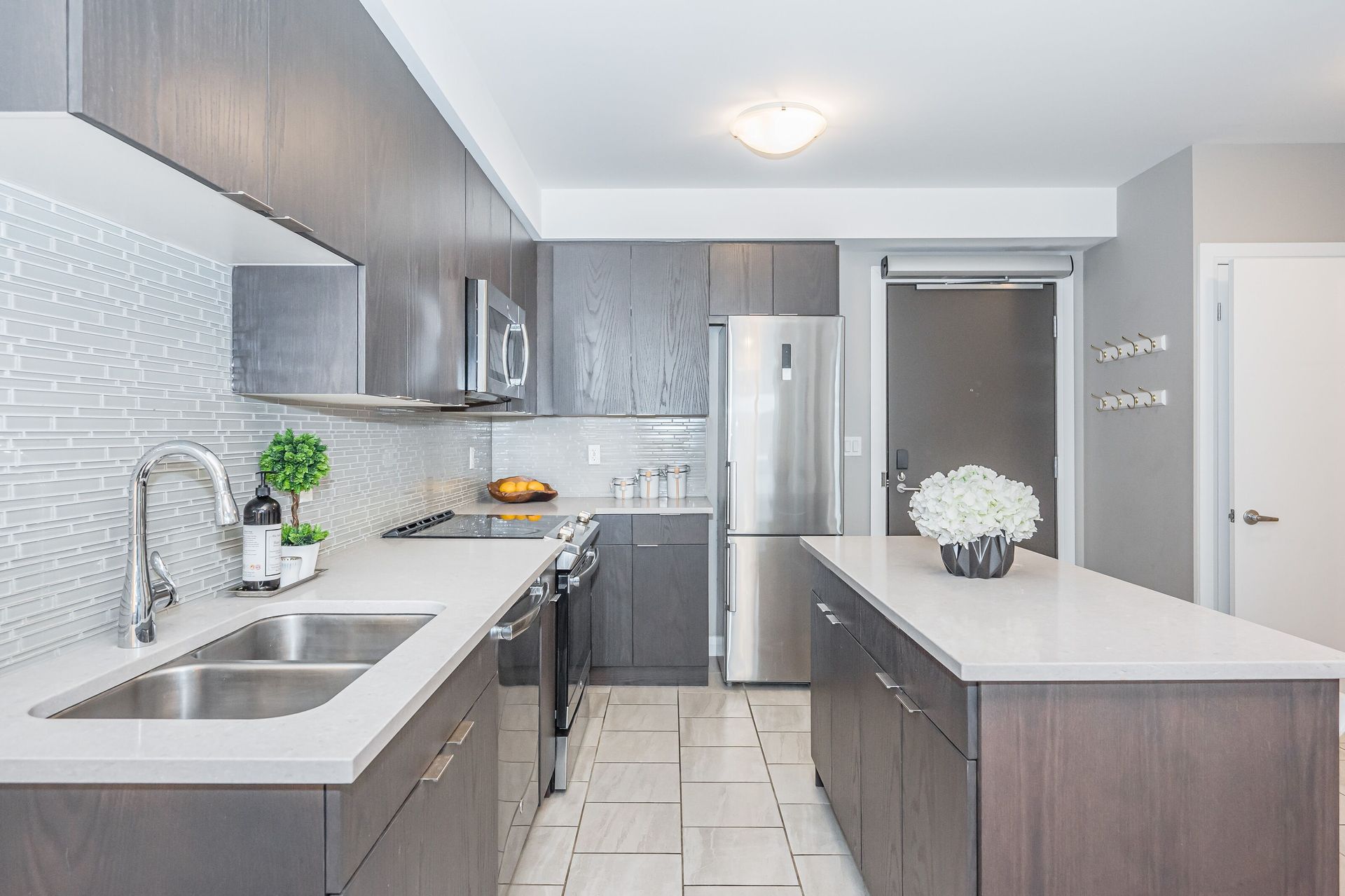 Modern gray kitchen with stainless steel appliances, white countertops, and a large island