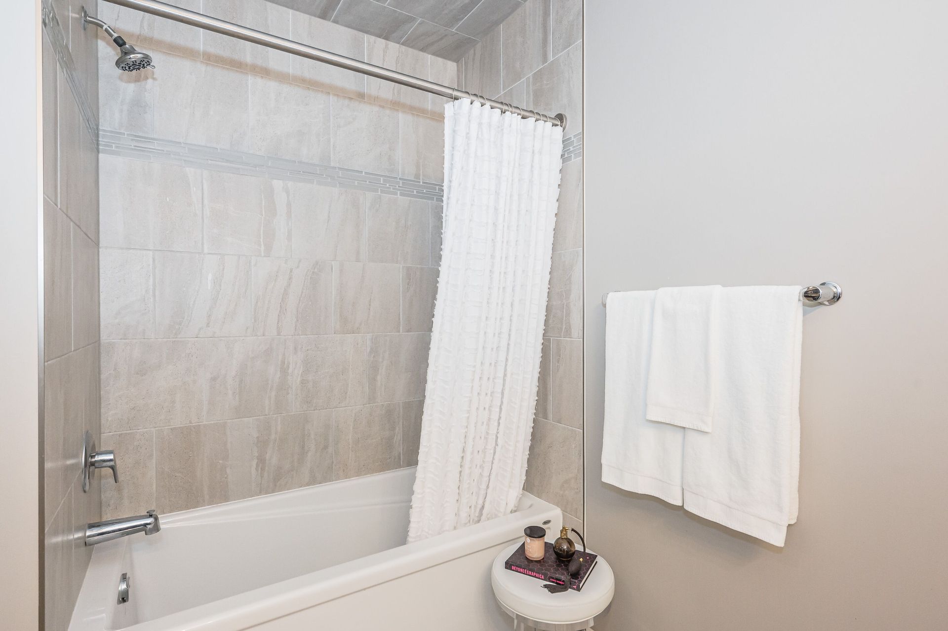 Small bathroom with a white tub, shower curtain, towel rack, and towel hanging on the wall.