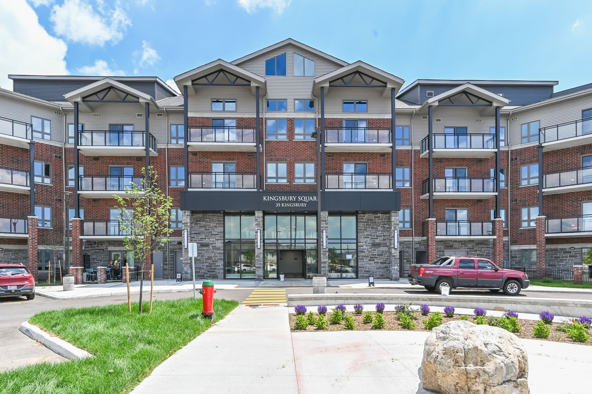 Modern apartment building with balconies, glass storefronts, and landscaped walkway in front