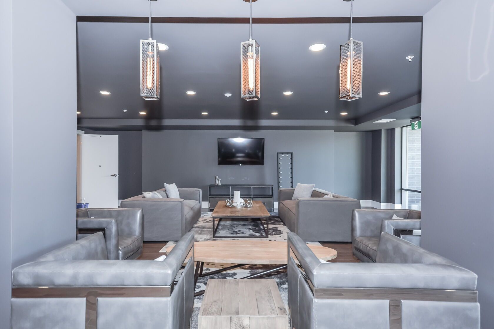 Modern living room with gray sofas, pendant lights, coffee table, and wall-mounted TV