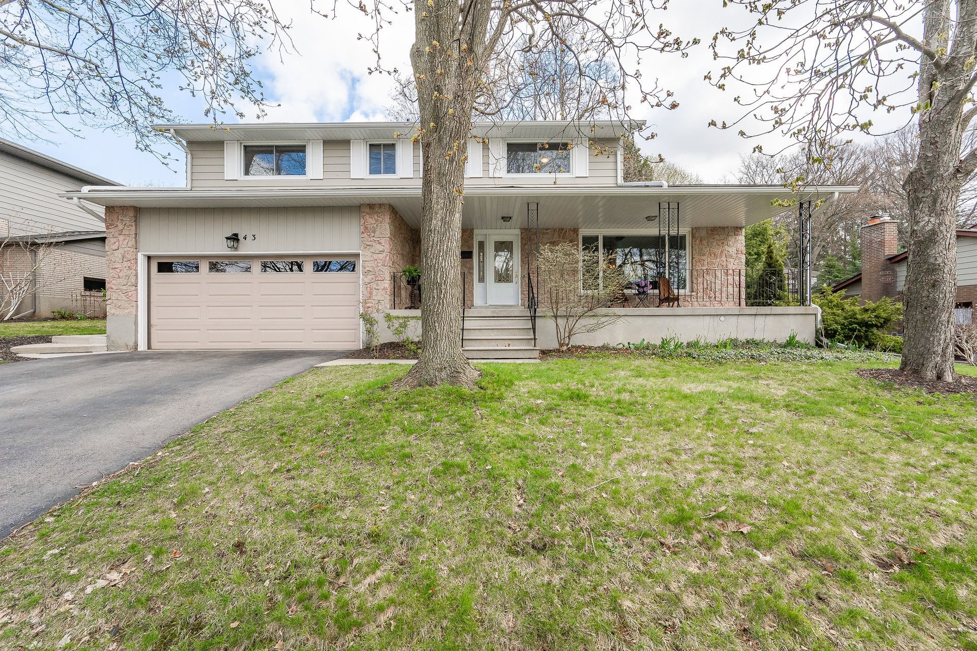 Two-story suburban house with attached garage, front lawn, and bare trees