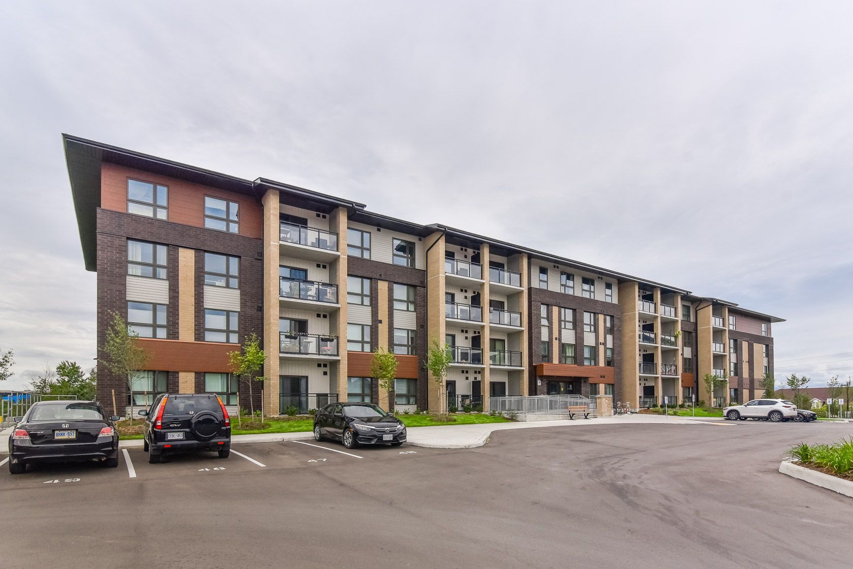 Modern apartment building with parked cars and overcast sky