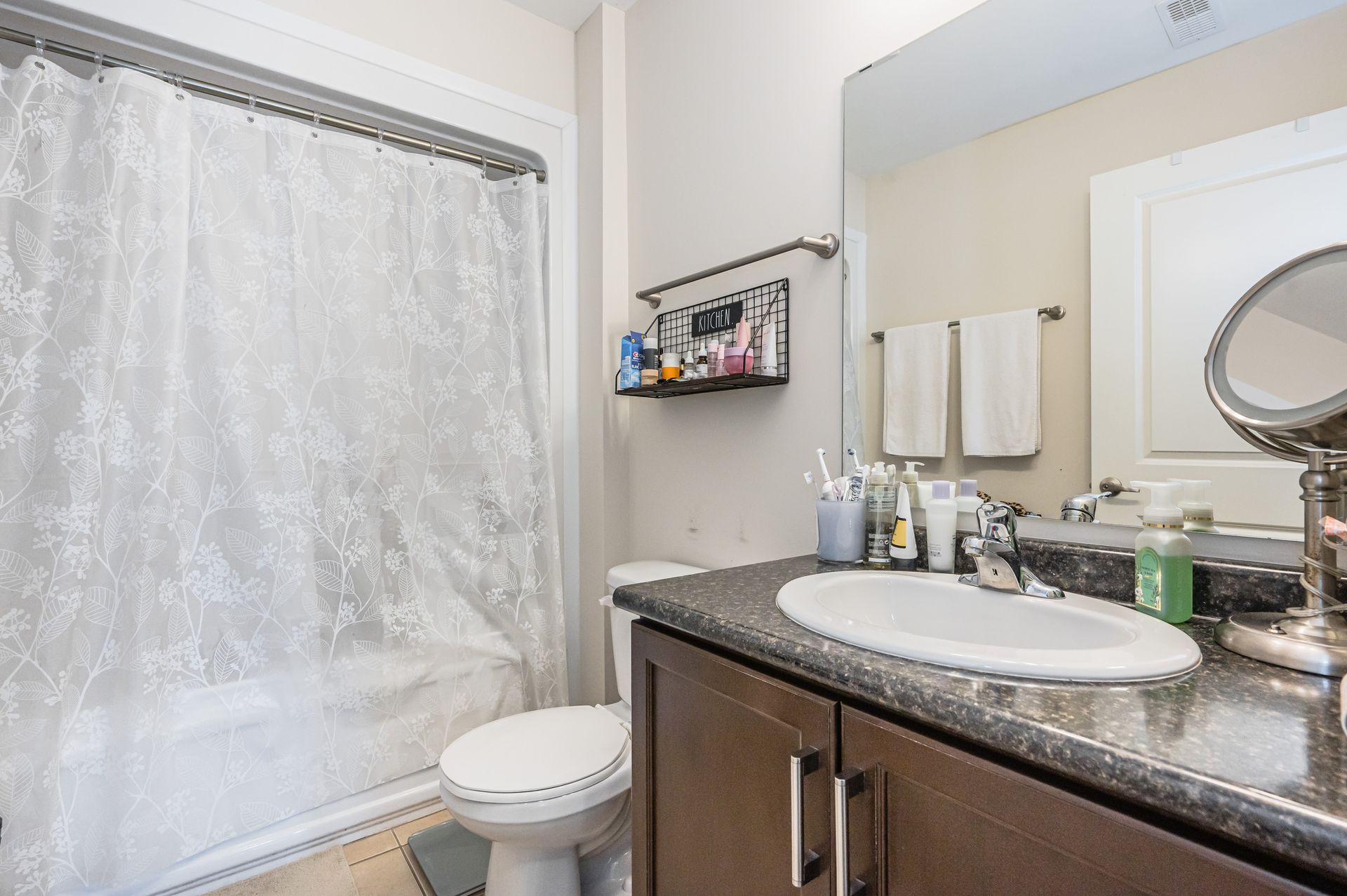 Small bathroom with a shower curtain, toilet, and granite vanity with sink and mirror