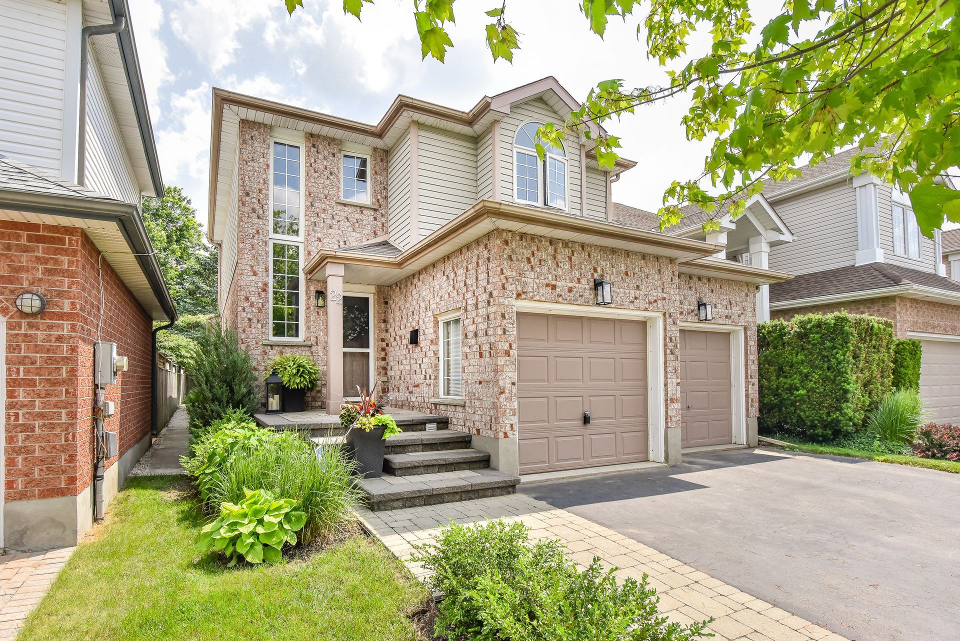 Suburban two-story brick house with garage, driveway, and landscaped front yard