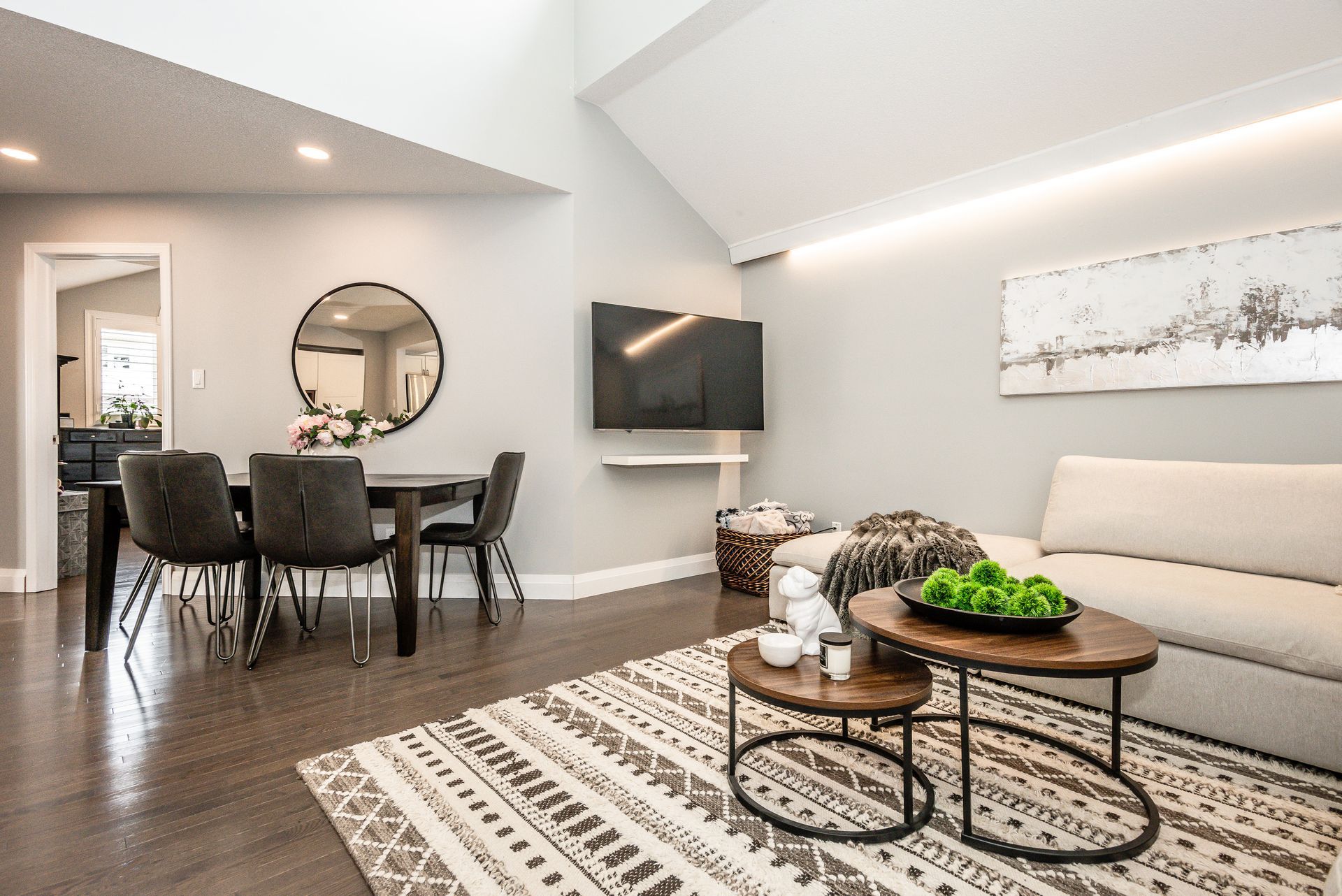 Modern open-concept living room with dining area, gray walls, sectional sofa, and geometric rug